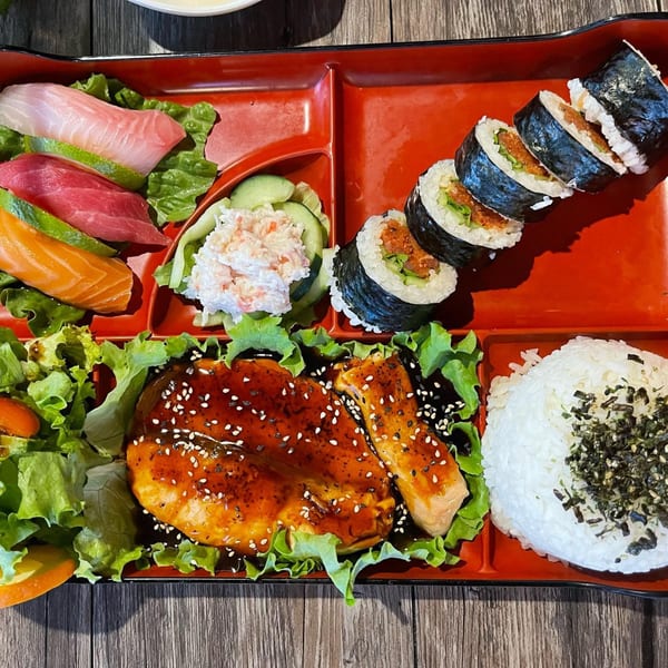 Awesome Sushi bento box with sashimi, spicy tuna rolls, teriyaki chicken, rice, and salad.