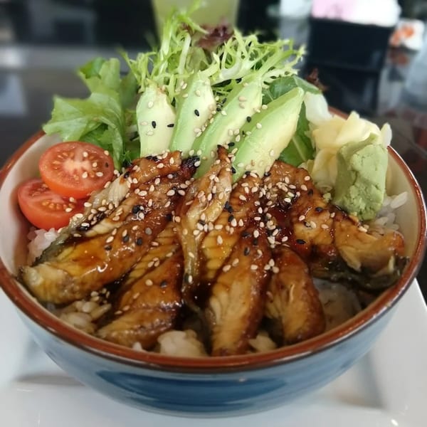 Awesome Sushi's unagi donburi with grilled eel, avocado, lettuce, tomatoes, and sesame seeds.