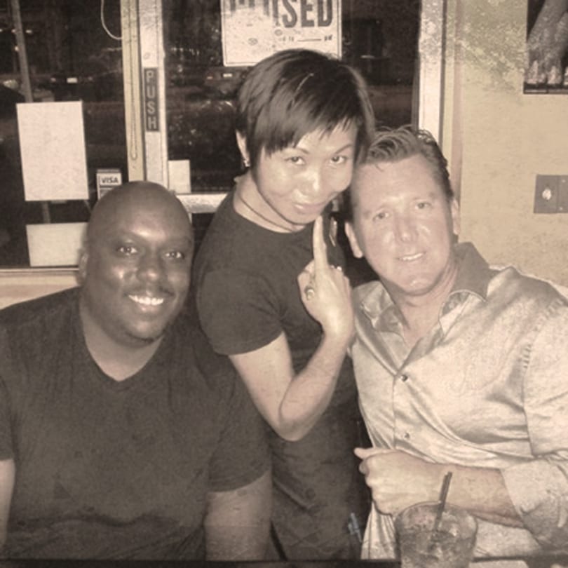 Three smiling people posing for a photo at Awesome Sushi, with one person pointing playfully.